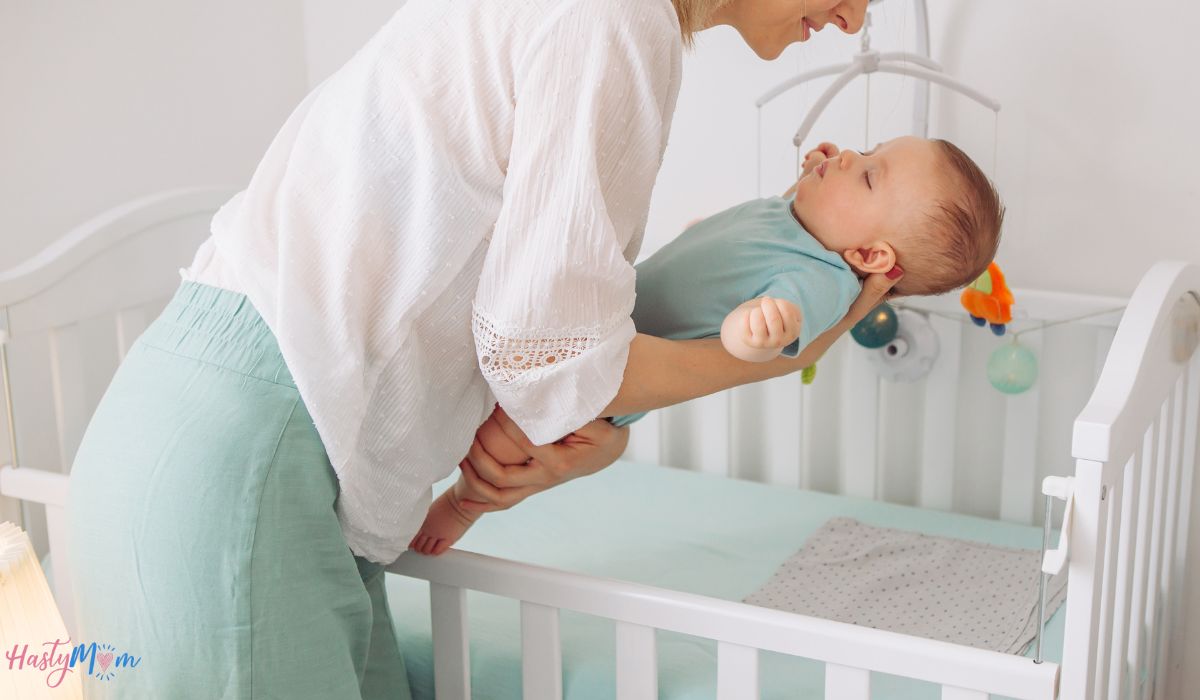 mom putting baby in crib